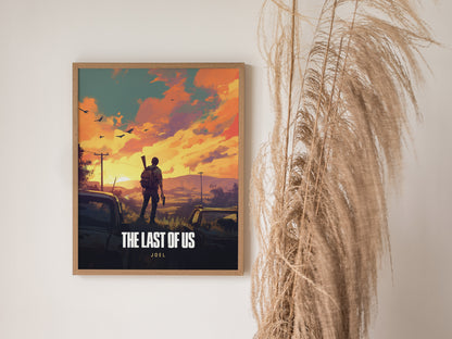 A framed poster of The Last of Us featuring a silhouetted figure with a backpack against a dramatic sunset sky. Tall dried plants are placed beside the artwork.