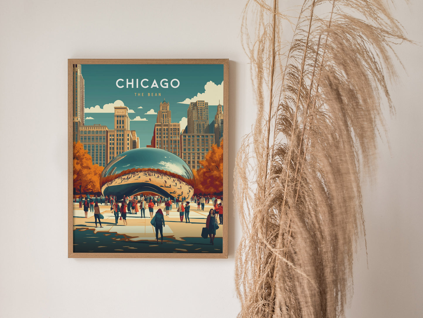 A framed poster of Chicagos Cloud Gate, featuring vibrant colors and autumn trees, hangs on a wall beside tall, dried plants.