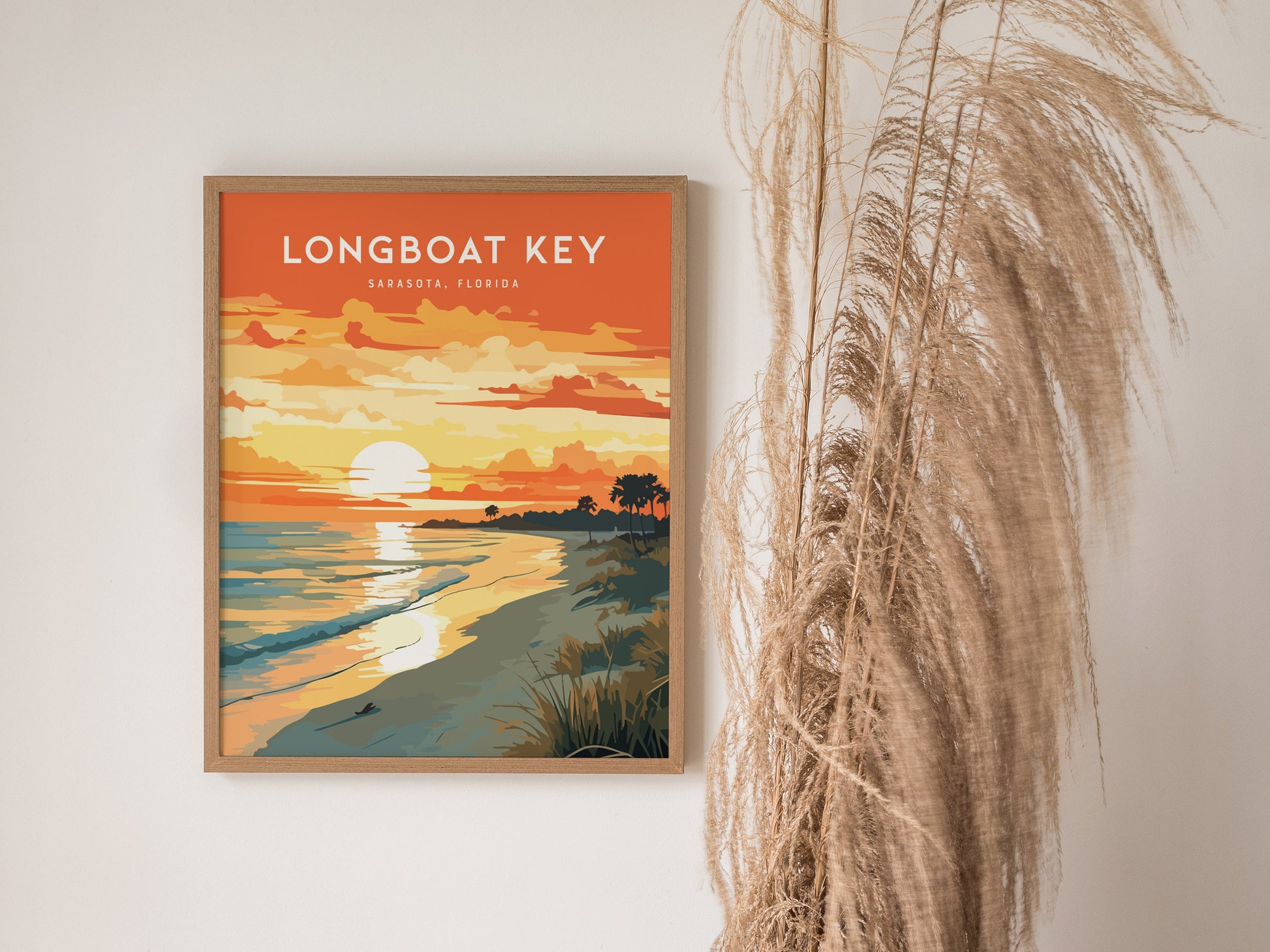 A framed poster titled Longboat Key, Sarasota, Florida depicts a vibrant sunset over a beach with sea oats and palm trees. The artwork is displayed on a wall next to tall, dried grasses.