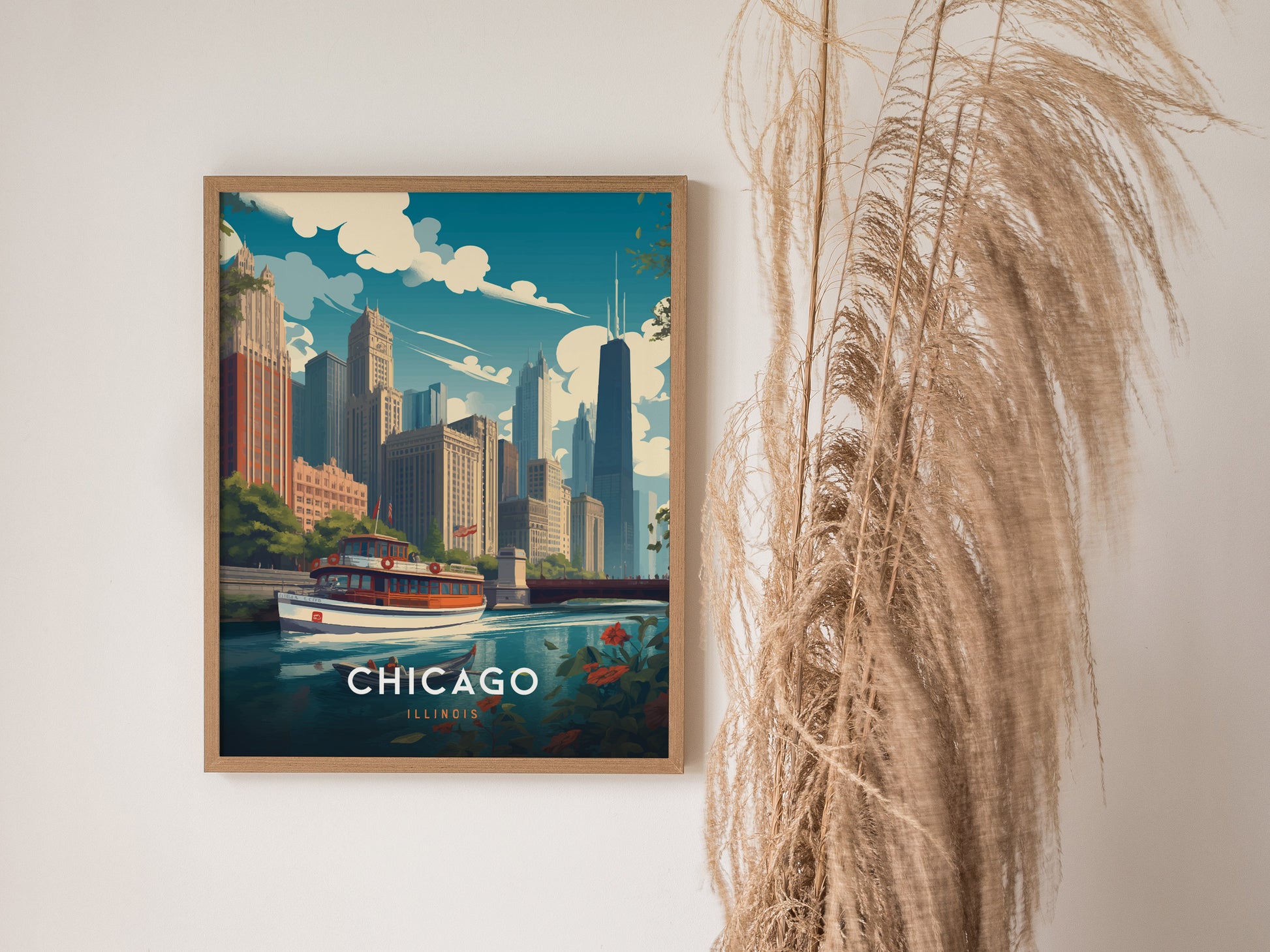 Framed art print of downtown Chicago, featuring skyscrapers and a riverboat, hangs beside tall dried pampas grass against a neutral wall. The word Chicago is prominently displayed.