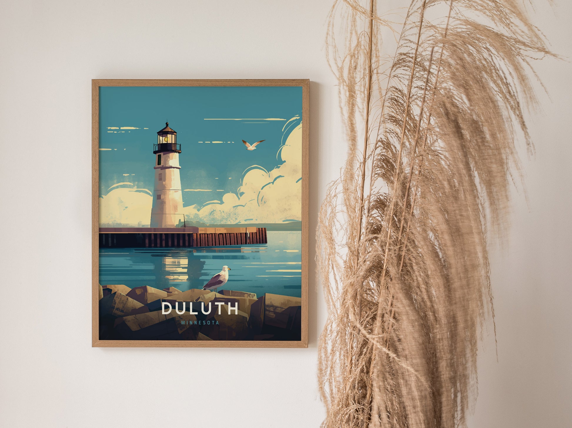 Framed poster of a lighthouse by calm waters, featuring a seagull and blue sky, displayed next to pampas grass. Text reads DULUTH MINNESOTA.