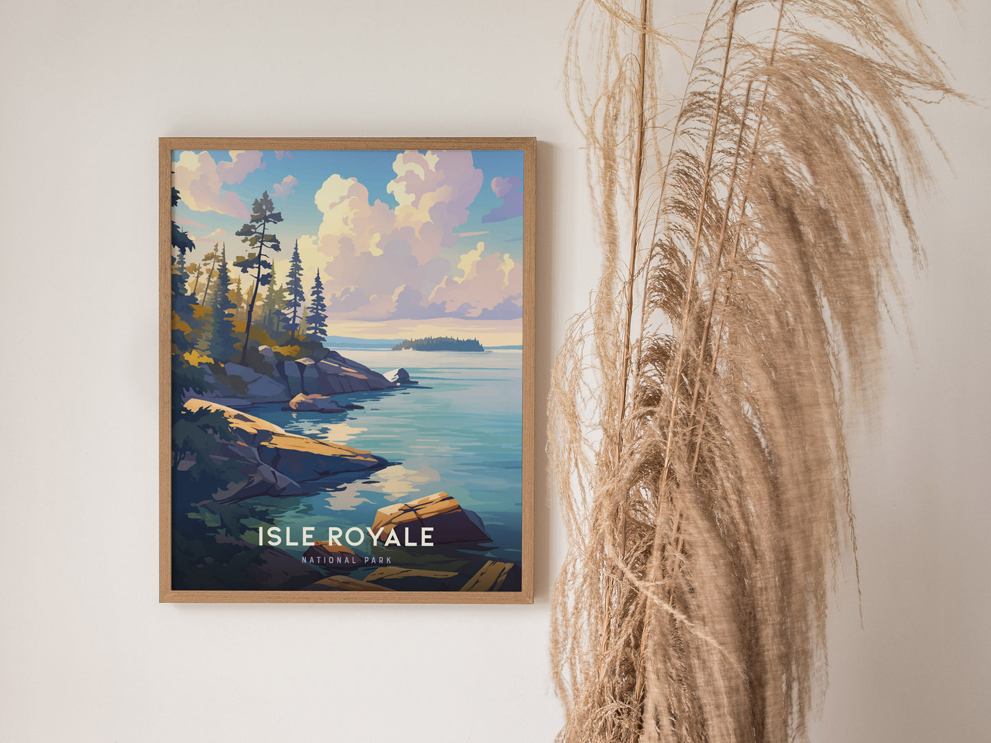 A framed Isle Royale National Park poster featuring a scenic view of rocky shorelines and pine trees by a calm lake, with pampas grass decor nearby.