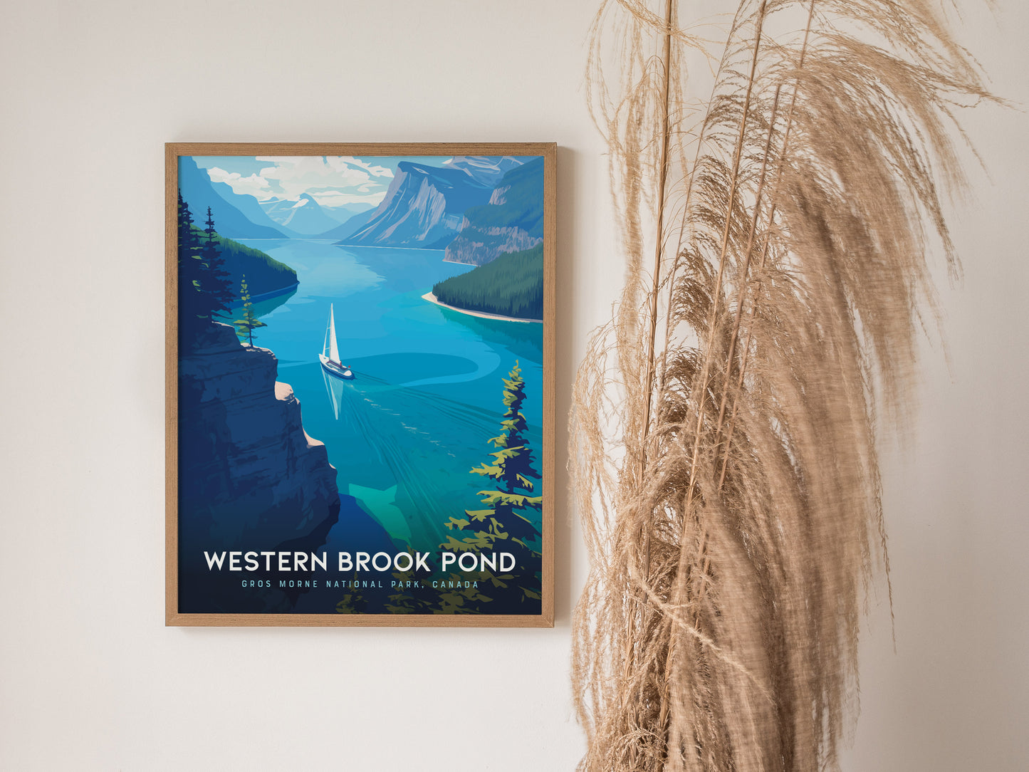 A framed poster of Western Brook Pond hangs on a wall, depicting a sailboat on vibrant blue waters surrounded by cliffs and trees, with pampas grass nearby.