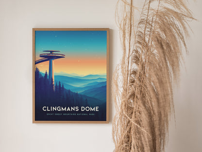 A framed poster of Clingmans Dome is displayed on a white wall, featuring an illustration of the observation tower amidst colorful mountain ridges at sunset. Dried pampas grass decorates the right side.