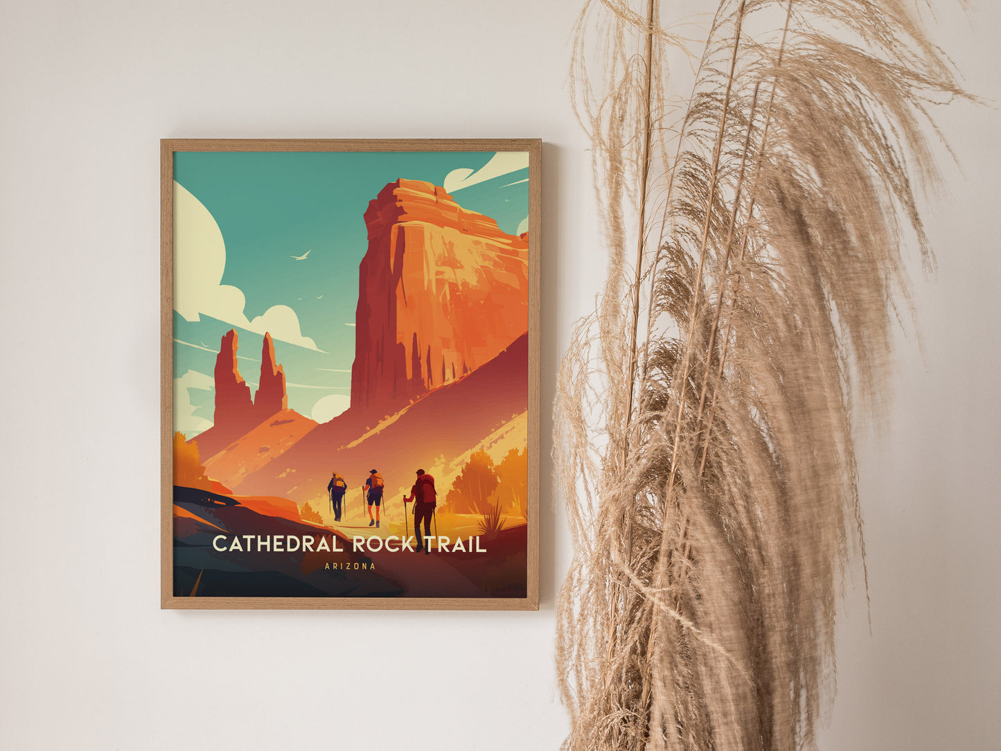A framed poster of Cathedral Rock Trail in Arizona hangs on a wall, featuring vivid red cliffs and hikers, with pampas grass decor adjacent.