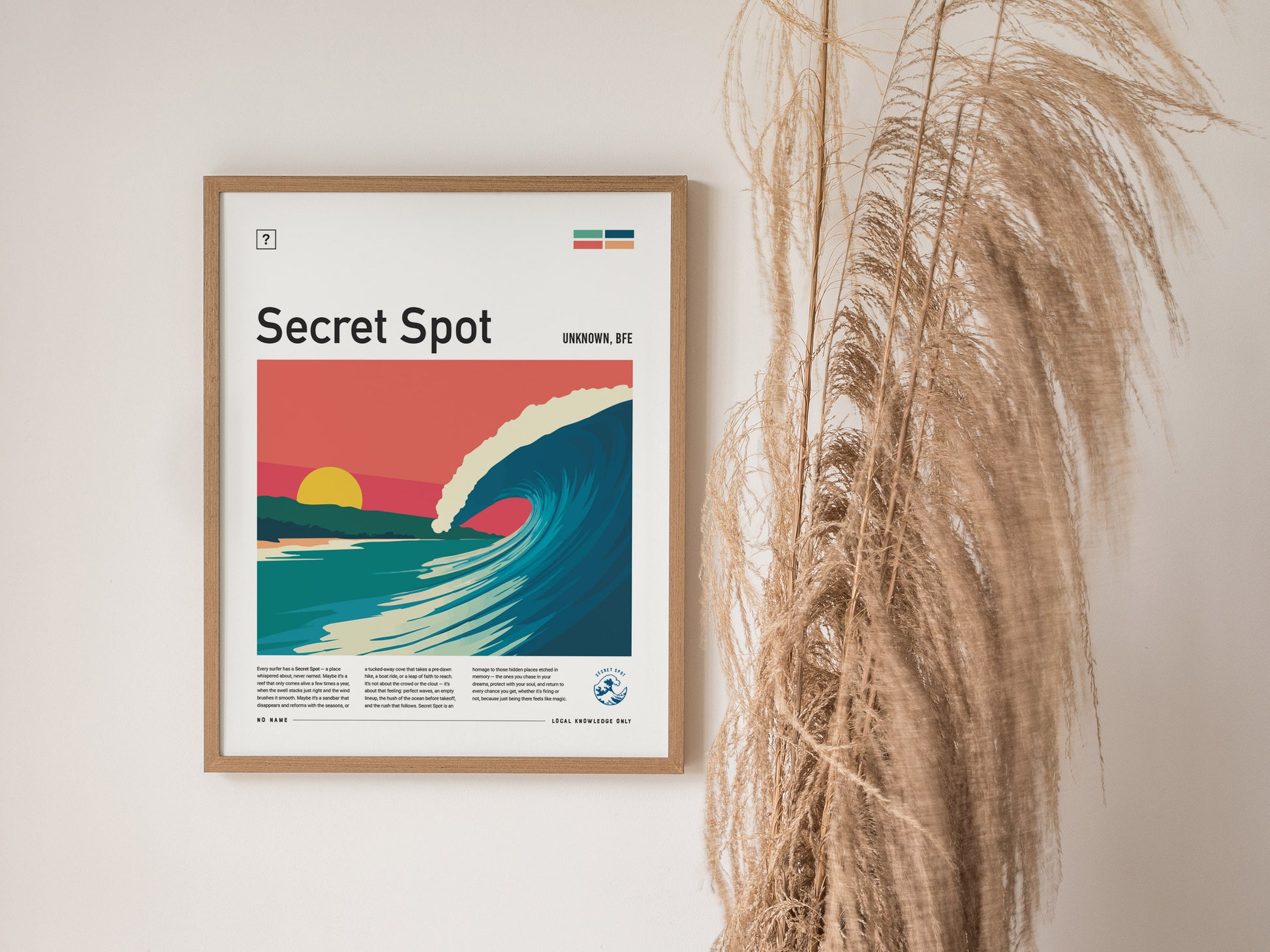 A framed poster titled Secret Spot features a vibrant illustration of a curling wave under a sunset with pastel colors. The artwork is accompanied by descriptive text and set against a neutral wall, complemented by decorative dried grass.