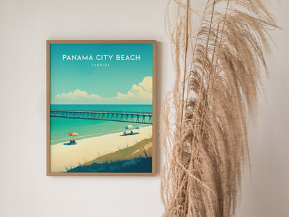 A framed poster of Panama City Beach, Florida, shows a vibrant beach scene with a pier, umbrellas, and turquoise water. Pampas grass decorates the space beside the poster.