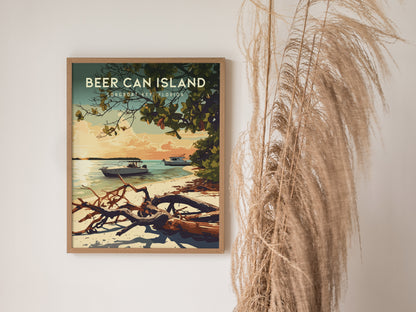 A framed poster of Beer Can Island, Longboat Key, Florida is displayed on a white wall. The artwork depicts boats in tranquil waters near a beach lined with driftwood, under a canopy of lush foliage. Pampas grass decorates the right side.