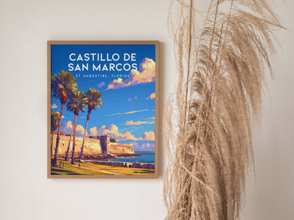 Framed poster of Castillo de San Marcos in St. Augustine, Florida, featuring palm trees and vibrant blue skies. Its displayed on a wall next to decorative dried grasses.