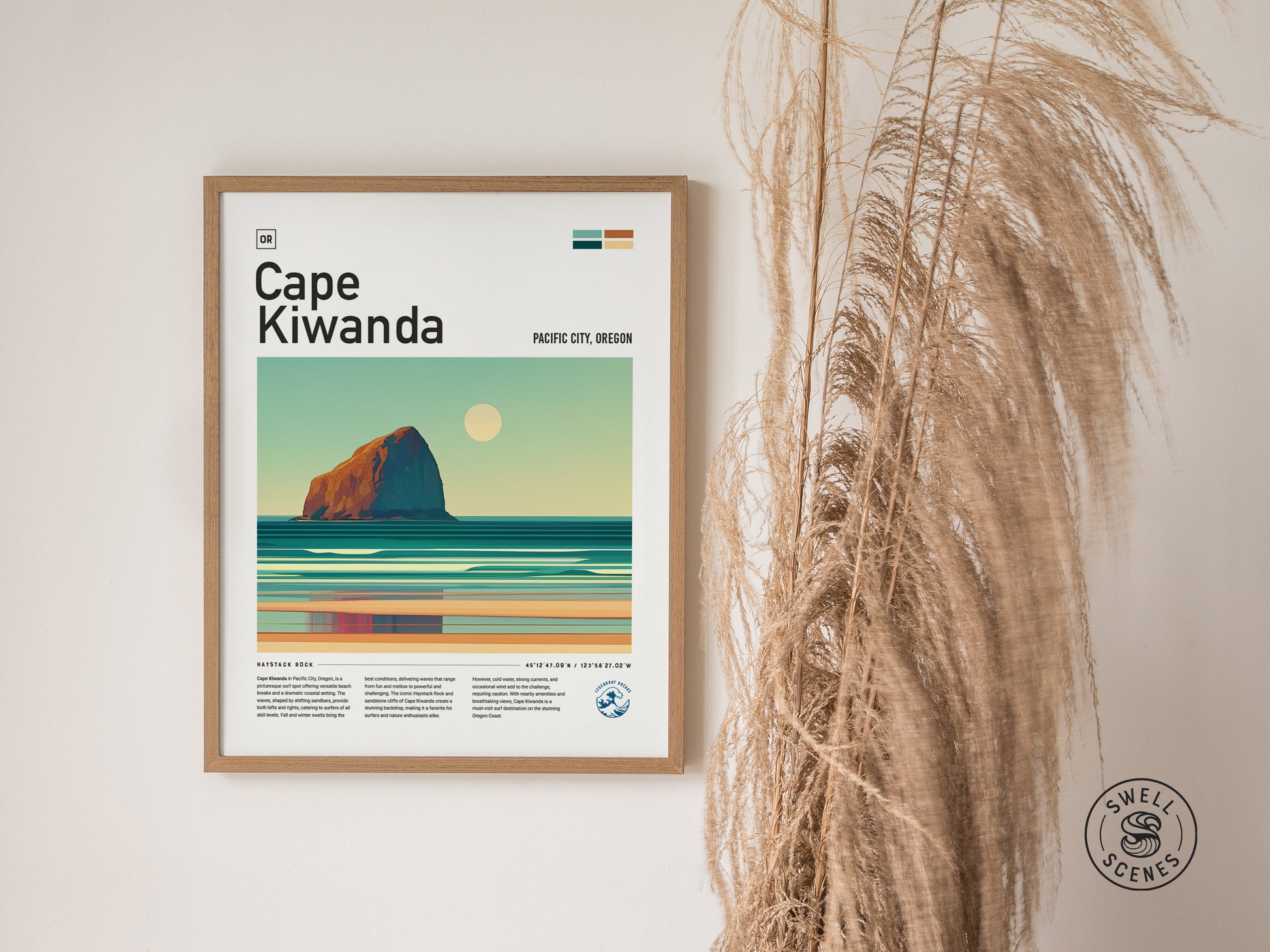 Framed Cape Kiwanda poster featuring a stylized illustration of Haystack Rock and ocean waves under a setting sun. The poster is displayed on a wall beside dried pampas grass.