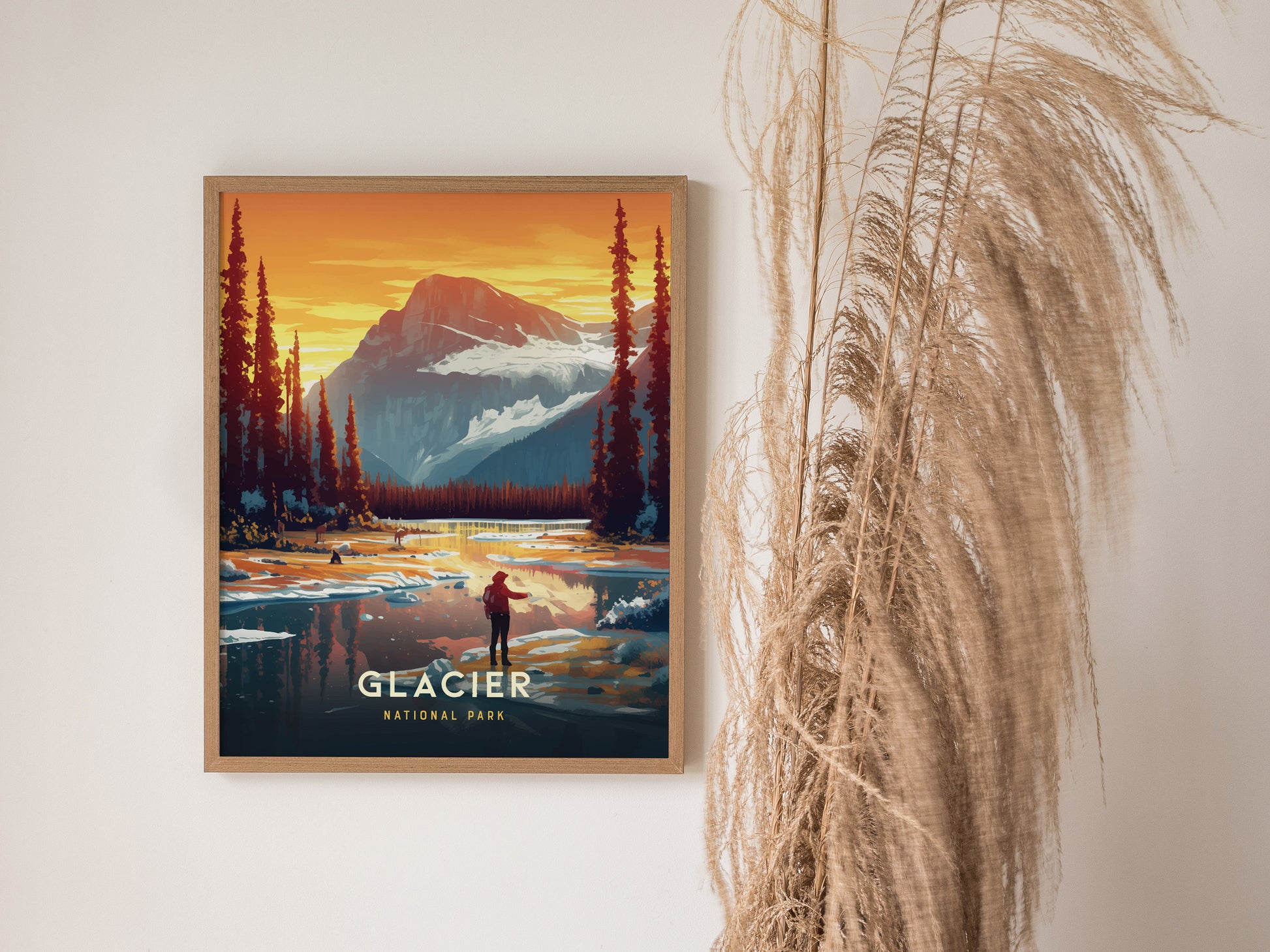 Framed Glacier National Park poster featuring a vibrant landscape with a mountain, lake, and trees against a sunset sky. Decorative dried grass is visible alongside the artwork.