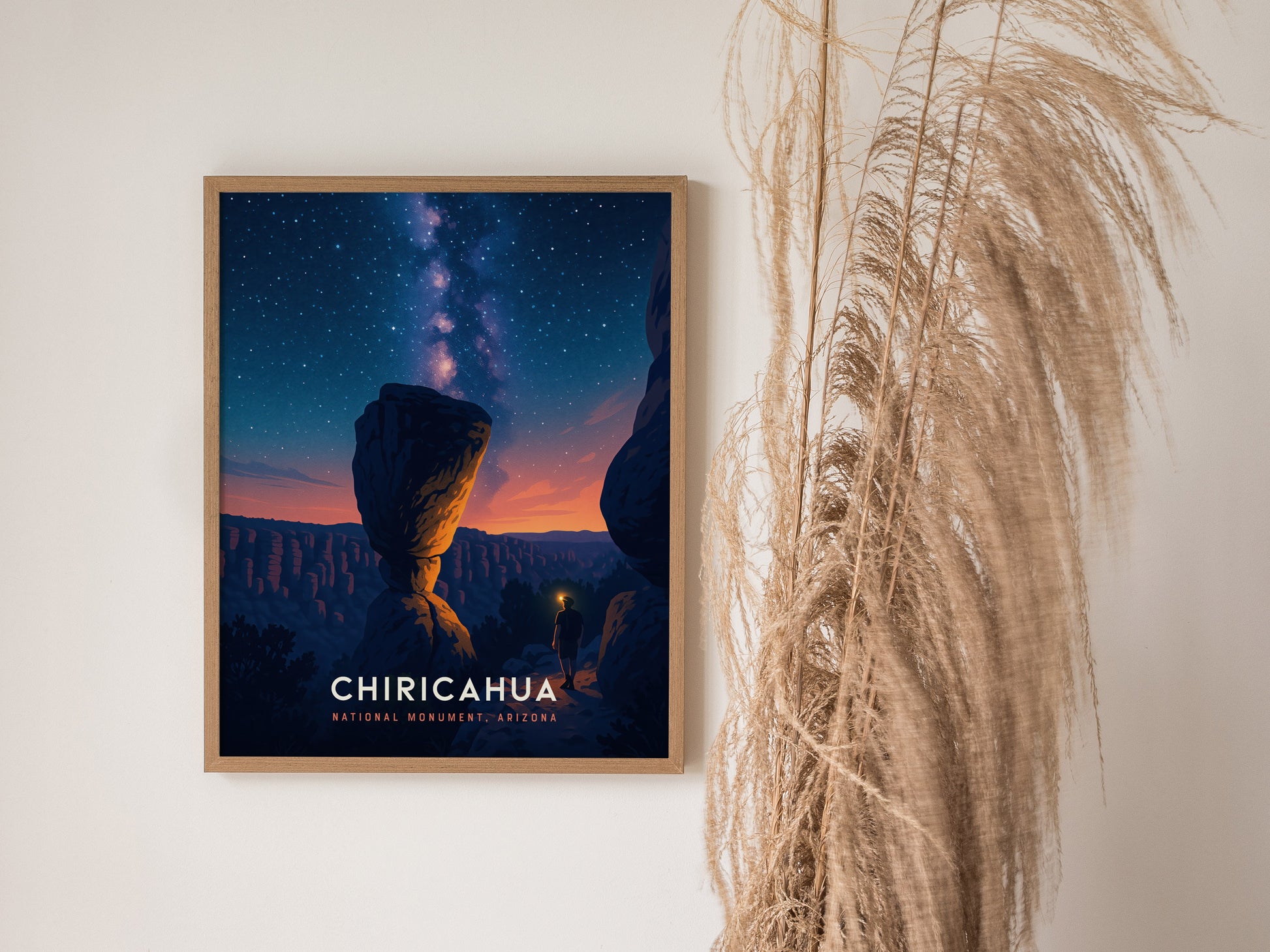 Framed poster of Chiricahua National Monument at night, featuring a person exploring rocky formations under a starry sky, showcasing vibrant blues and warm horizon hues.