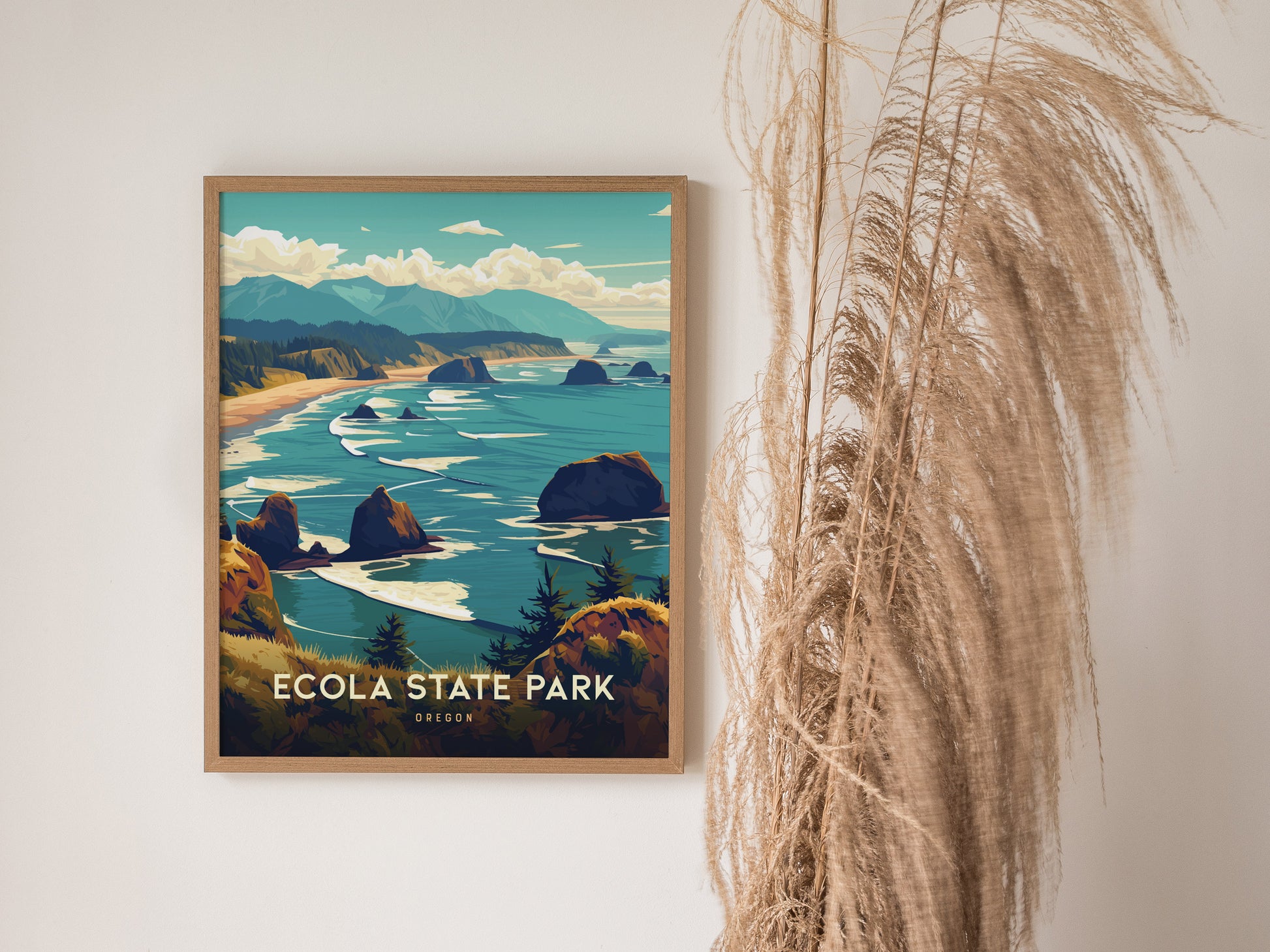 A framed art print of Ecola State Park featuring lush green headlands, rugged cliffs, and the Pacific Ocean. Decorative dried grass stands beside the artwork.