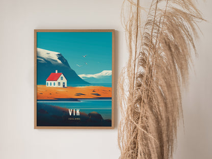 A framed illustration of a coastal scene with a red-roofed house, mountains, and flying birds, set against a beige wall with decorative dried grasses.