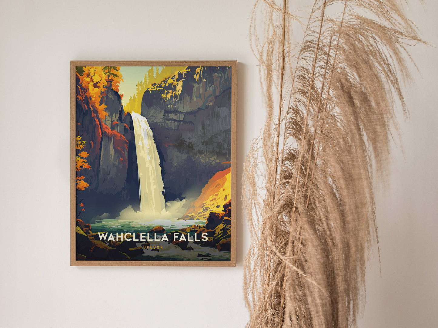 A framed poster of Wahclella Falls features a vibrant waterfall surrounded by colorful cliffs, displayed on a wall next to tall, dried decorative grasses.