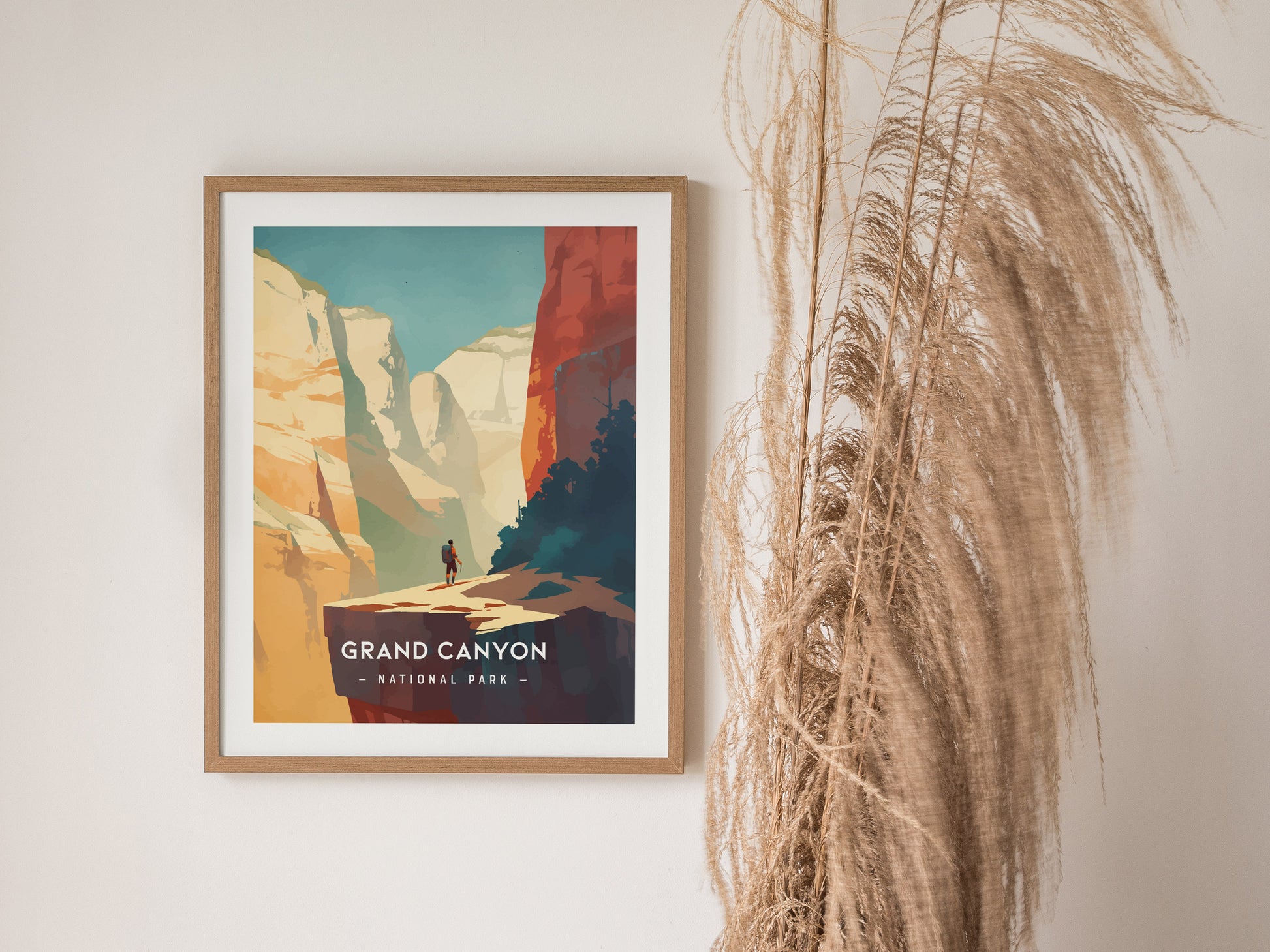 Framed wall art featuring a minimalist illustration of the Grand Canyon is displayed against a white wall, next to tall, dried grasses.