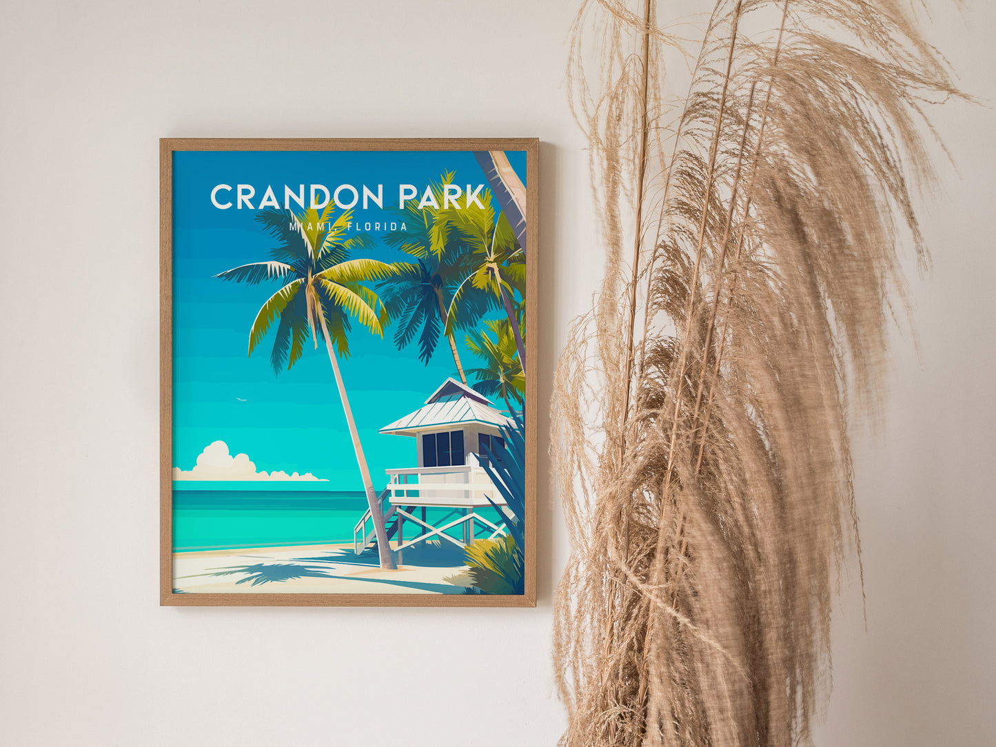 A framed poster of Crandon Park Beach, Miami, Florida, features vibrant palm trees and a white lifeguard tower against turquoise waters. The artwork is displayed next to tall.