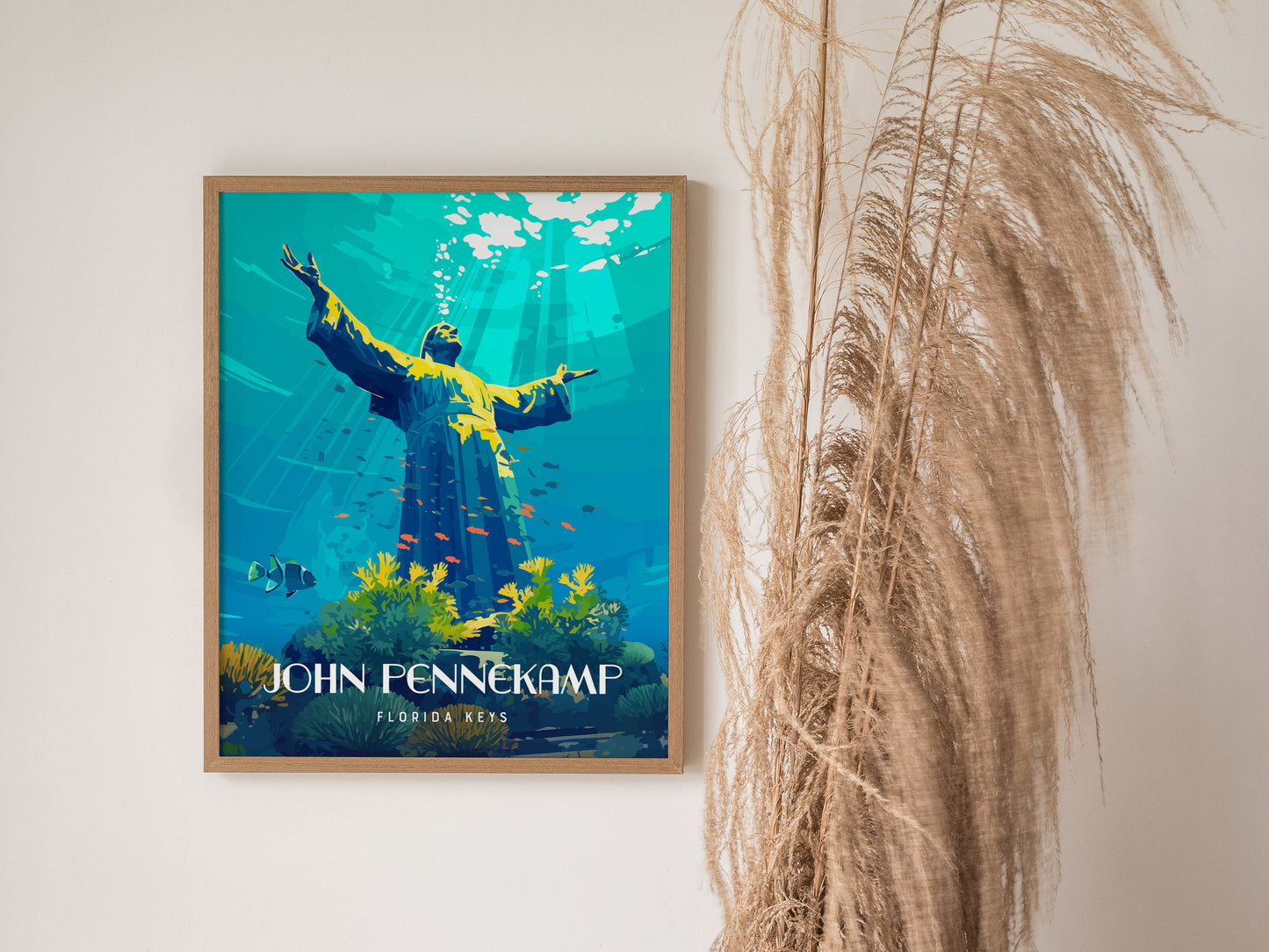 A framed poster of an underwater scene features a statue with outstretched arms surrounded by vibrant coral and fish. Dried grass decorates the space beside the artwork.
