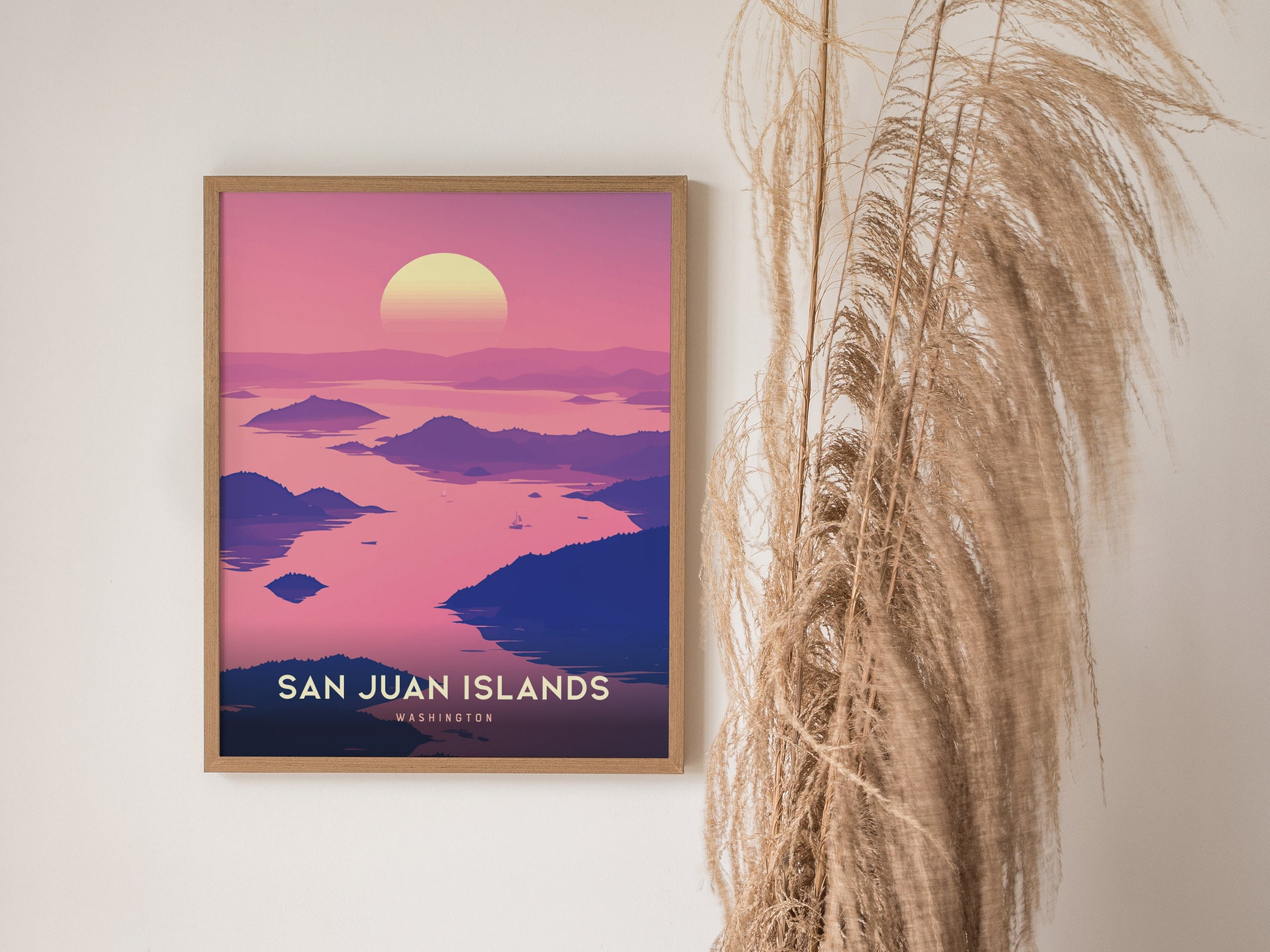 A framed poster of the San Juan Islands with a pink and purple sunset, surrounded by serene waters and islands. Decorative grasses are positioned beside it.