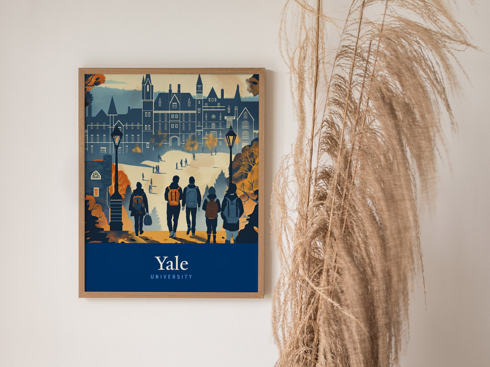 A framed poster of Yale University features students walking on campus with Gothic architecture in the background. Tall, dried pampas grass decorates the right side of the scene.