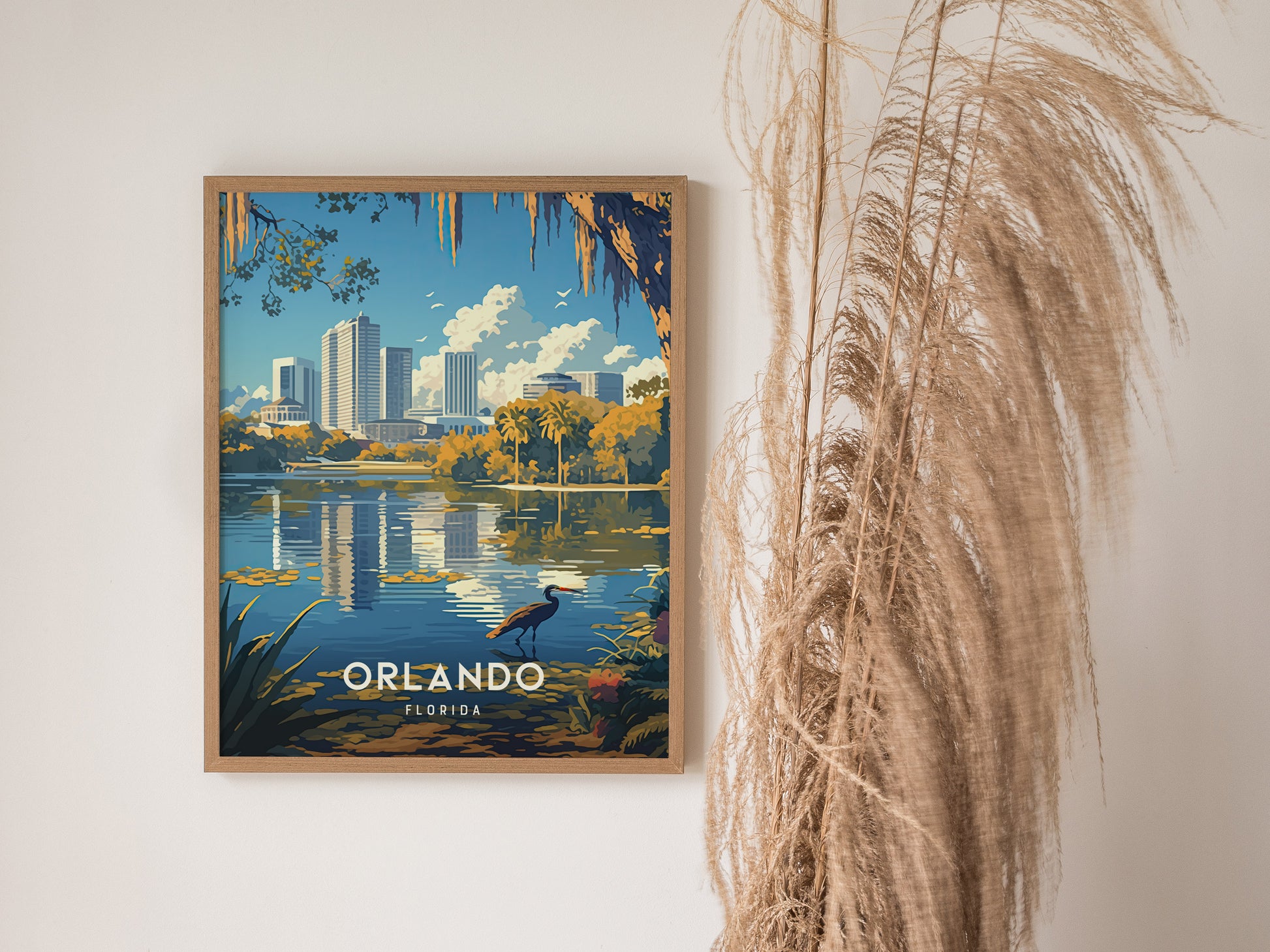 A framed poster of Orlandos Lake Eola skyline features a heron and reflections in the water, with tall pampas grass nearby.
