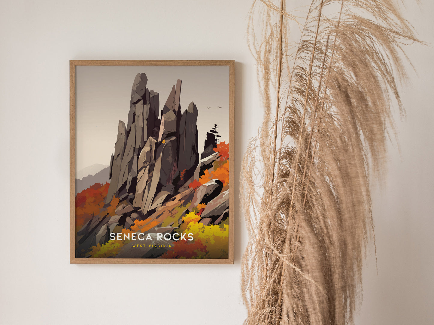 A framed poster of Seneca Rocks in West Virginia is displayed on a wall, featuring a stylized illustration of the rocky formation with autumn foliage. Tall dried plants are nearby.