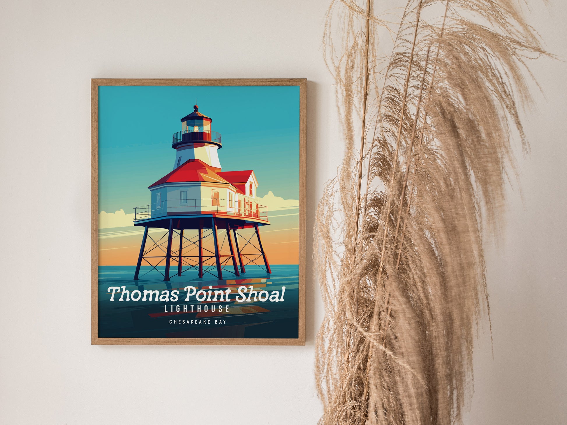 A framed poster of Thomas Point Shoal Lighthouse with vibrant colors is displayed on a wall beside decorative dried pampas grass.