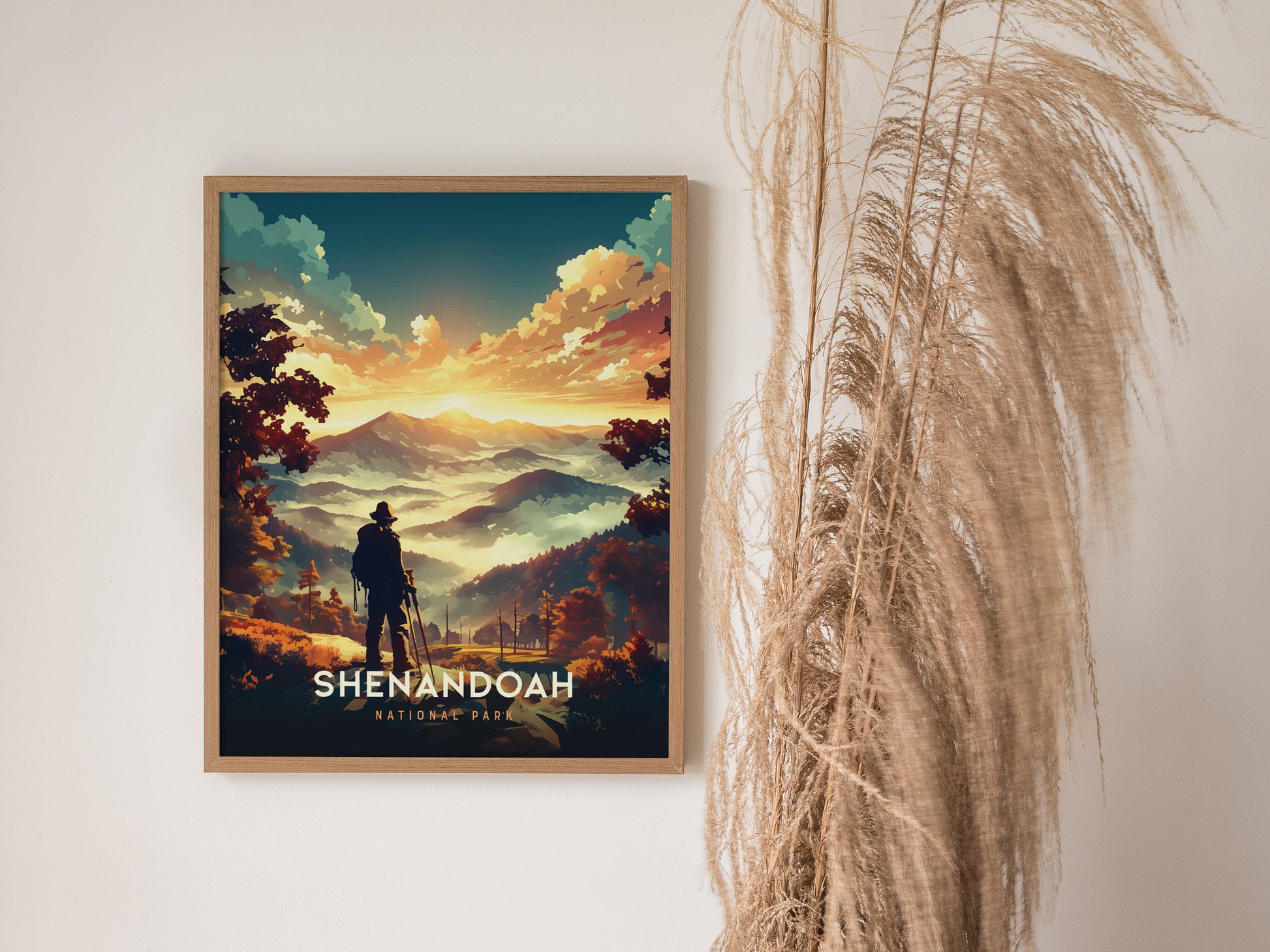 Framed poster of Shenandoah National Park features a silhouetted hiker overlooking rolling mountains under a vibrant sunset. Tall dried grass decorates the adjacent wall.
