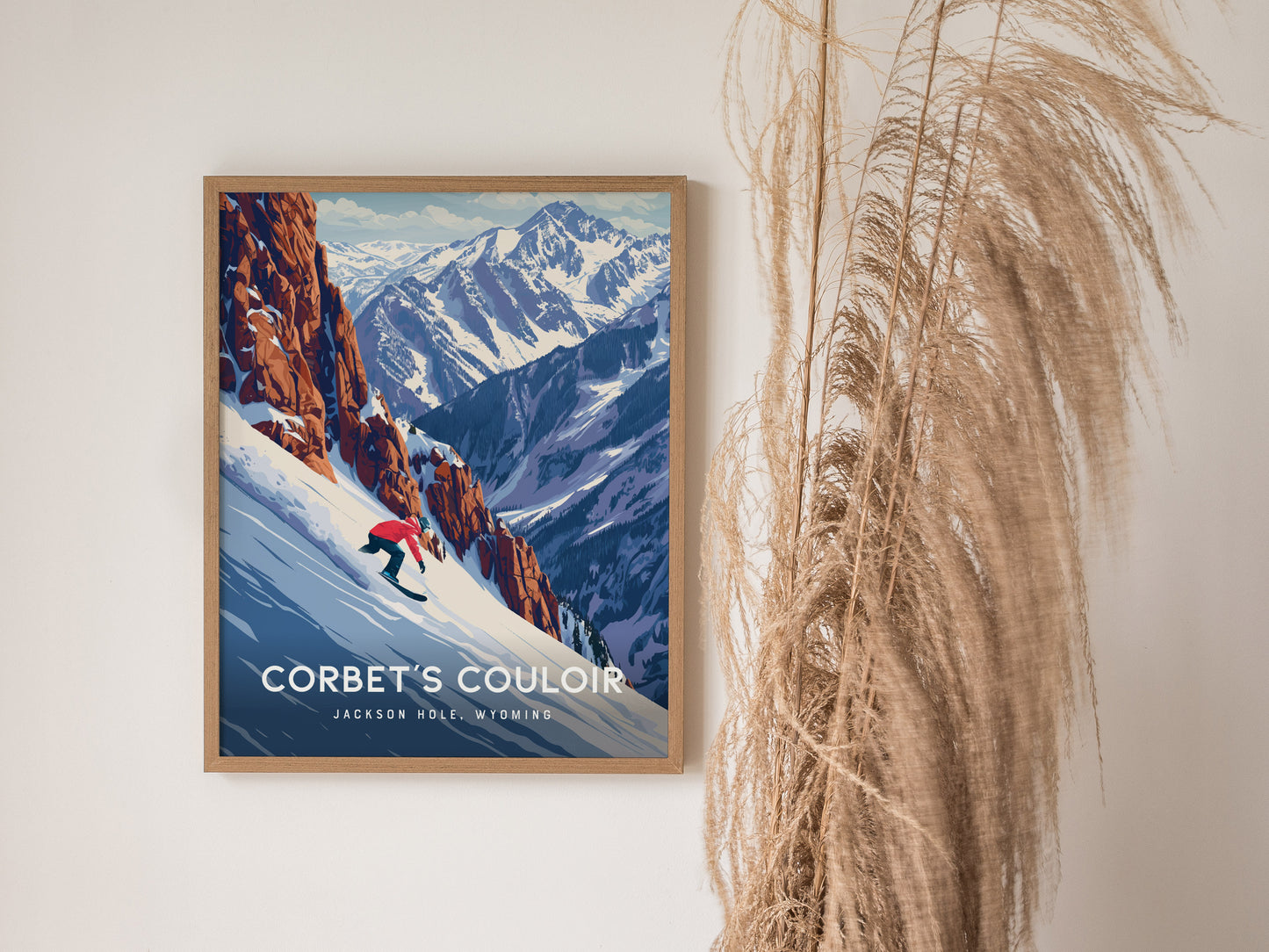 A framed poster on a wall features a snowboarder descending a snow-covered slope with rugged mountains in the background. Tall dried grasses are positioned beside the artwork.