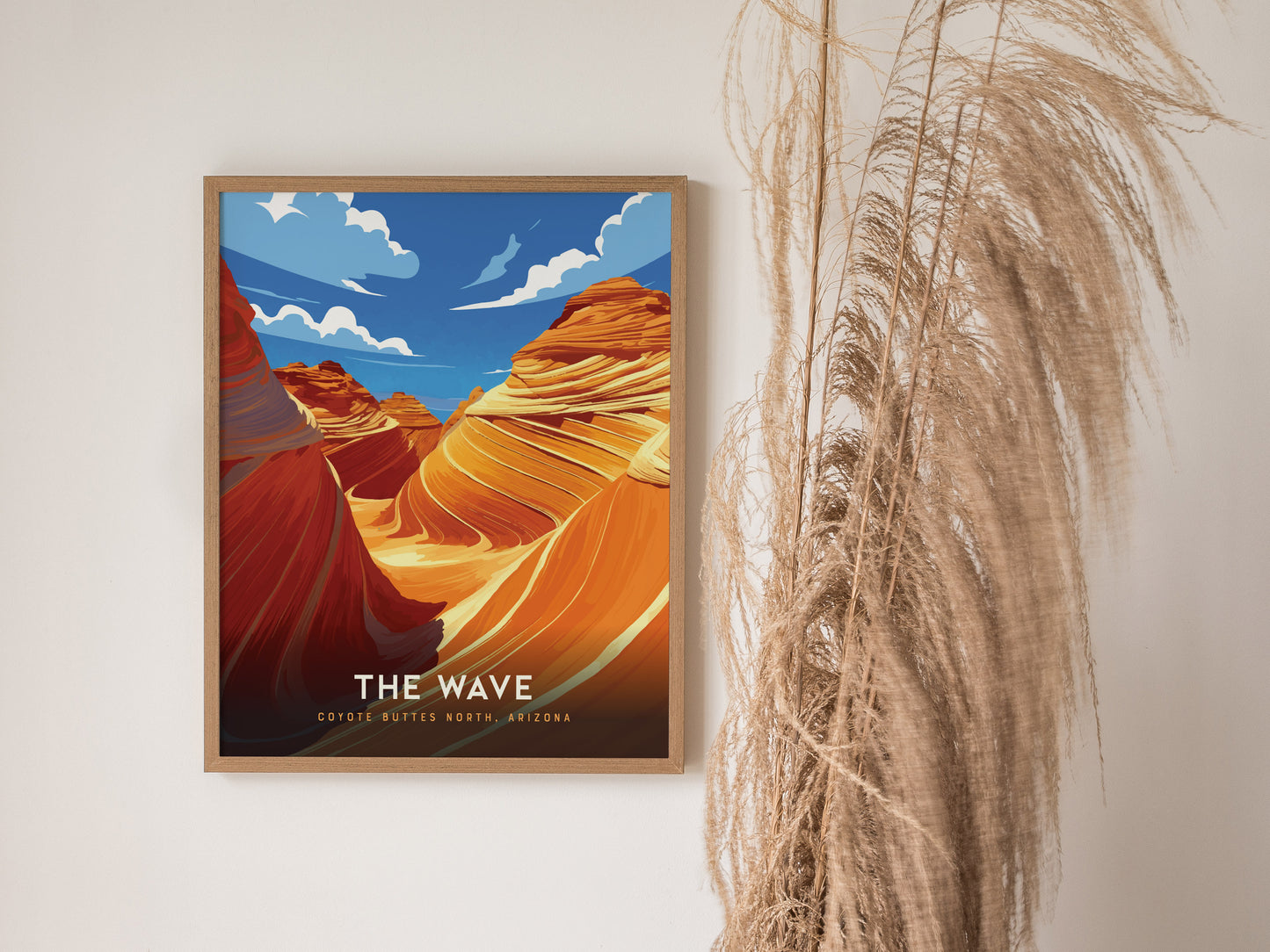 A framed poster of The Wave in Coyote Buttes, Arizona, featuring vibrant swirling sandstone formations against a bright blue sky, is displayed next to tall, wispy dried grass.