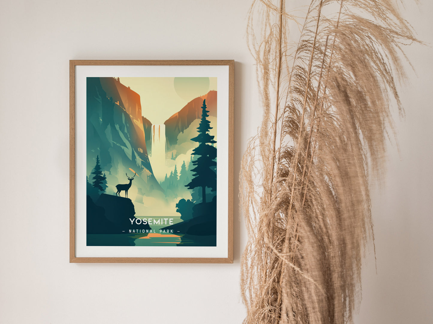 A framed poster of Yosemite National Park features a minimalist design with a deer silhouette, a waterfall, and tall pine trees. Its displayed on a wall with decorative dried grasses.