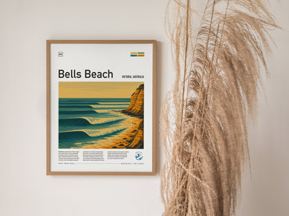 Framed poster of Bells Beach, Victoria, Australia, with stylized waves and cliffs, hangs on a wall beside tall dried grass. The artwork features a warm color palette.