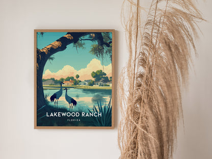 Framed Lakewood Ranch poster depicting a serene lakeside scene with two birds under a tree, houses in the background, and pampas grass beside it.