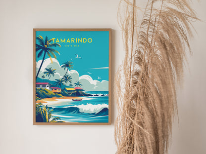 A framed poster features vibrant artwork of a tropical beach scene with palm trees and waves, titled Tamarindo Costa Rica. It is displayed next to dried pampas grass.