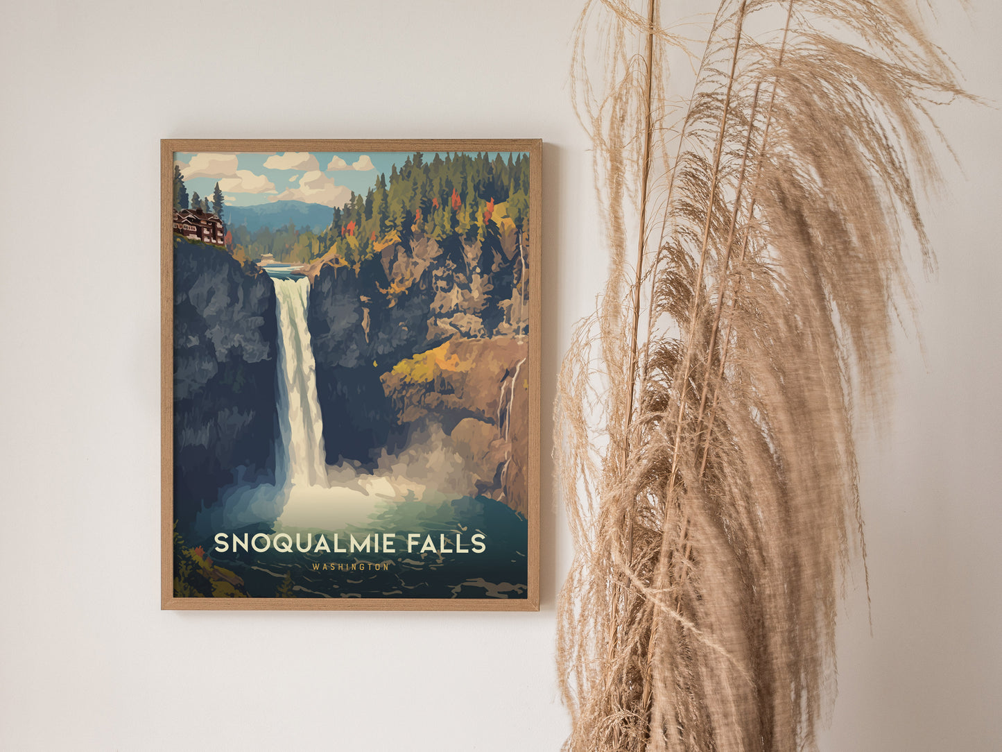 A framed poster of Snoqualmie Falls hangs on a white wall, depicting a waterfall surrounded by lush greenery. Tall, dried grasses are positioned to the right of the poster.