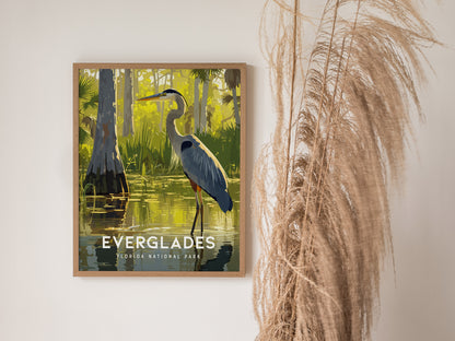 A framed poster of a Great Blue Heron in a serene Everglades scene hangs on a wall, next to tall, wispy dried grass.