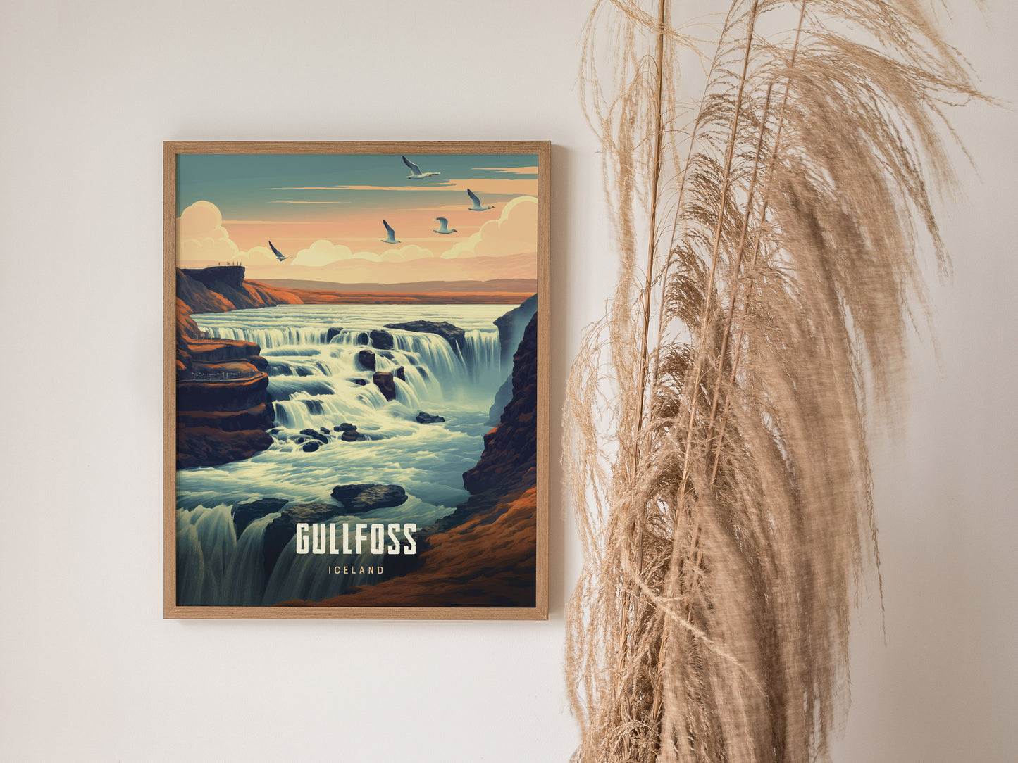 A framed poster of Gullfoss waterfall in Iceland shows cascading water under a pastel sky with birds flying. Tall, dried grasses are placed beside it for decorative effect.