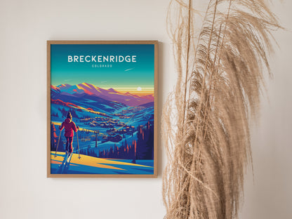 A framed poster of Breckenridge, Colorado, depicts a vibrant sunset over snow-covered mountains and a skier. Tall, dried grasses are positioned beside the artwork.