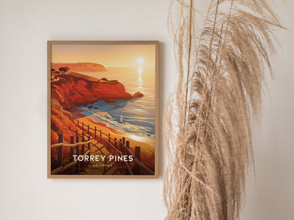 A framed poster of Torrey Pines, featuring vibrant coastal cliffs and a sunset over the ocean, is displayed next to tall, wispy dried grass.