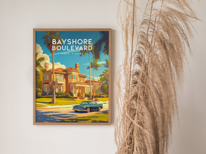 A framed poster of Bayshore Boulevard, Tampa, Florida, featuring a classic car and palm trees, hangs on a wall next to tall dried grasses.