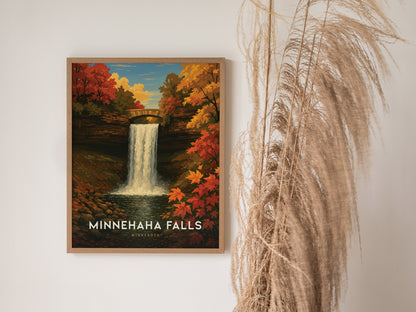A framed poster of Minnehaha Falls with vibrant autumn foliage hanging on a wall, accompanied by tall, wispy dried grasses to the right.