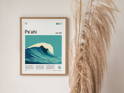 A framed poster depicting a stylized blue wave labeled Peahi hangs on a wall beside tall, dried pampas grass. The minimalist design adds a modern touch.