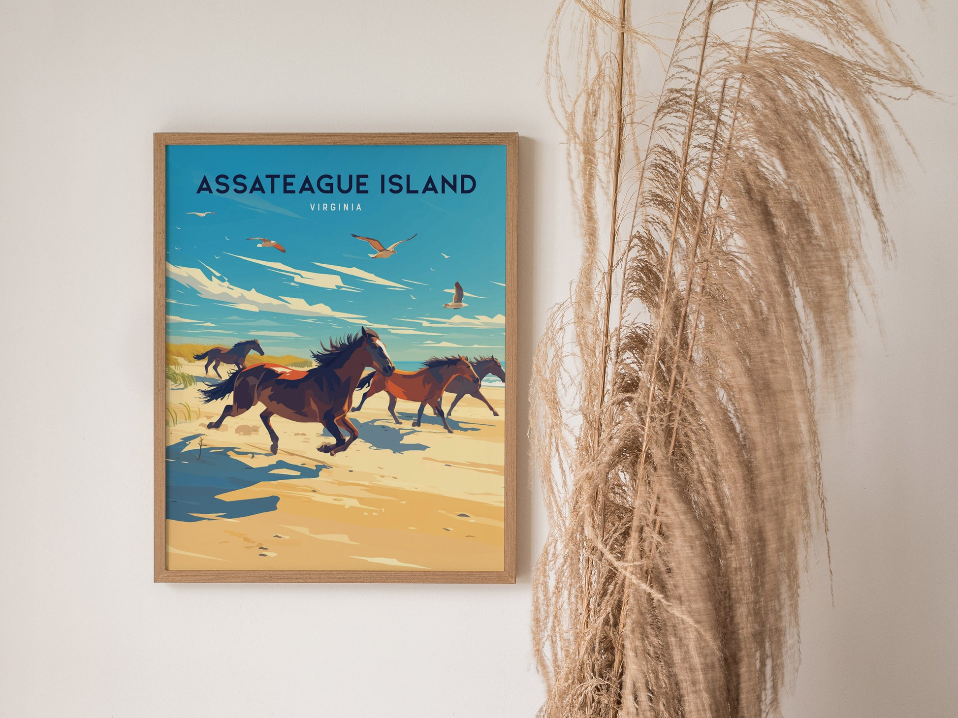 A framed poster of Assateague Island, Virginia, features wild horses galloping along a sandy beach under a blue sky with birds. Tall dried grasses are visible beside the poster.