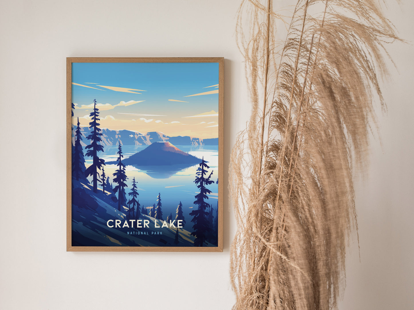 A framed poster of Crater Lake National Park features a stylized illustration of a serene lake surrounded by pine trees and cliffs, with dry plants nearby.
