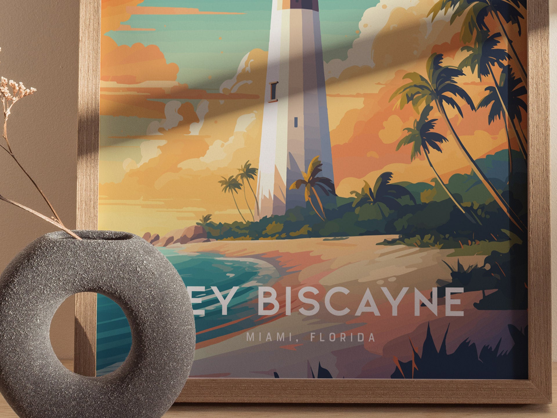 A framed poster of Key Biscayne Lighthouse features a stylized illustration with vibrant colors, palm trees, and a beach scene. A decorative gray vase sits in the foreground.