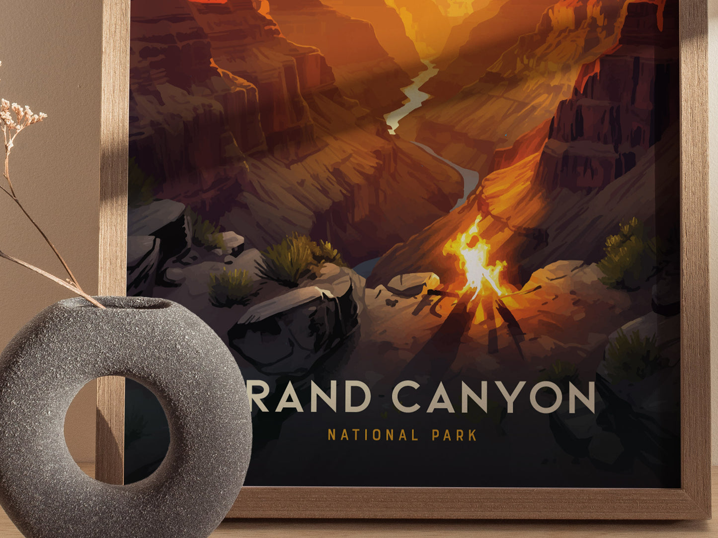 A framed poster of the Grand Canyon shows a vibrant sunset casting light on the canyons layers. A decorative round stone vase with dried flowers is in the foreground.