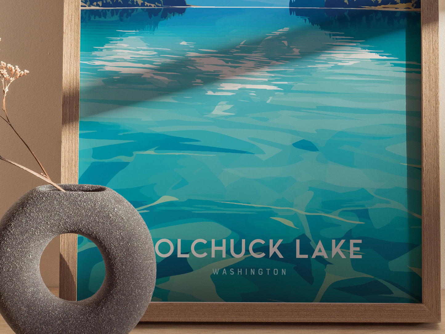 A framed poster of Colchuck Lake, Washington, features abstract turquoise water patterns. A circular stone vase with dried flowers is partially visible in the foreground.