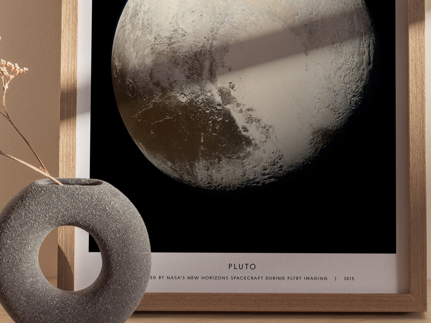 Framed image of Pluto with a decorative object on a table