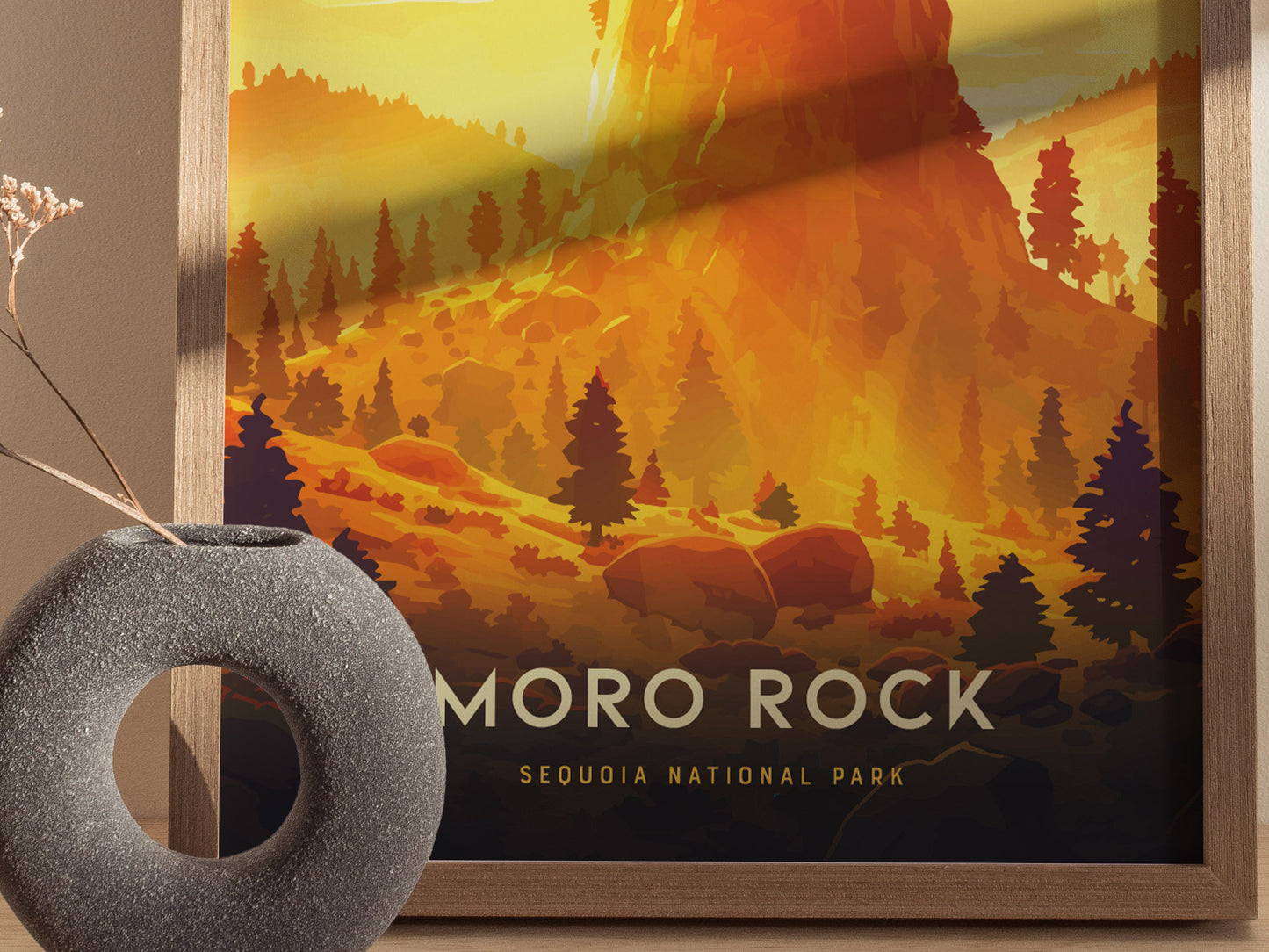 A framed poster of Moro Rock in Sequoia National Park features a vibrant orange landscape with silhouetted trees. A round, textured vase with dried flowers is placed nearby.