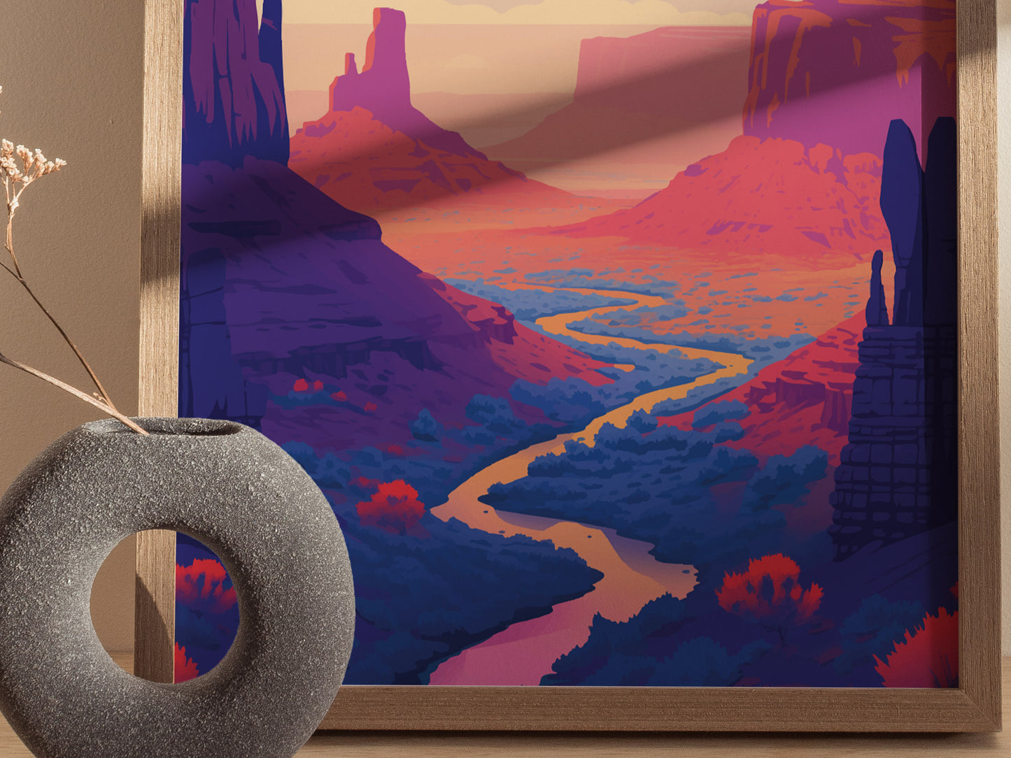 A vibrant poster features a winding river through a dramatic red rock desert landscape, with towering buttes under a colorful sky. A textured, round vase sits nearby.
